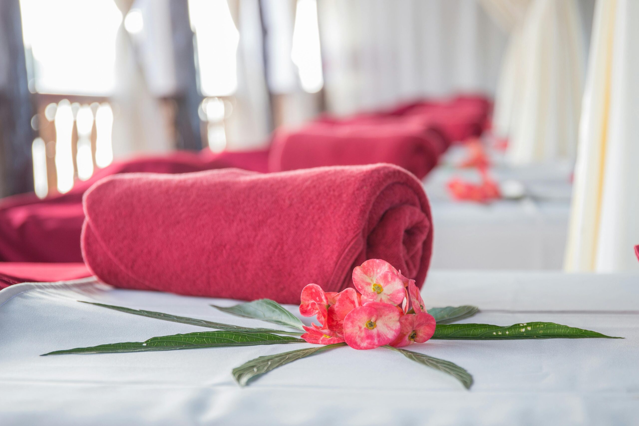 Home Elegant spa interior featuring red rolled towels and vibrant flowers, perfect for relaxation.