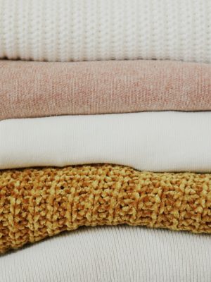 A close-up view of neatly stacked, warm fabrics showcasing various textures and colors.