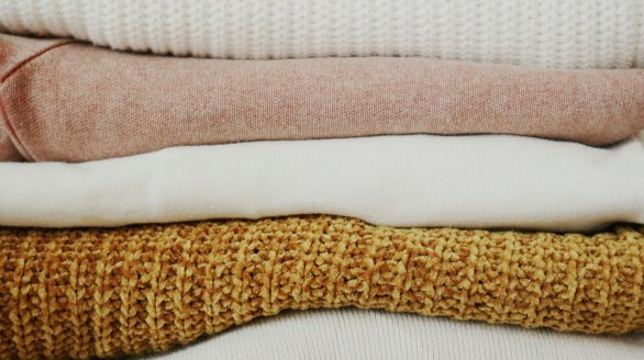 A close-up view of neatly stacked, warm fabrics showcasing various textures and colors.