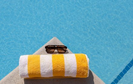 pexels photo 31789278 31789278 Relax by the pool with striped towel and sunglasses under the summer sun.